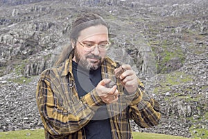 A geologist man in clean clothes with glasses holds two stones in their hands