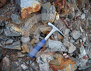 Geologist rock pick over natural rocks background