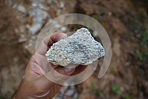 A geologist`s hand is holding a piece of granite rock.