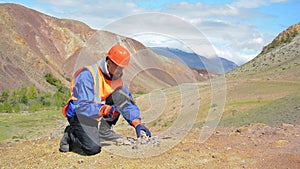 Geologist tap a rock formation with a hammer