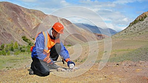 Geologist tap a rock formation with a hammer