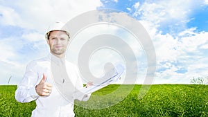 Geologist in white helmet on green meadow with drawings in hands holds his thumb up. Engineer builder on construction site