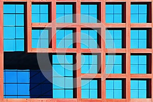Geometric architectural background of blue and coral color. Skyscraper glass windows.