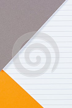 Geometric background with gray and orange colored paper and blank lined paper page. Top view, copy space