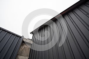 Geometric industrial dark composition of a concrete gray wall and an iron corrugated roof
