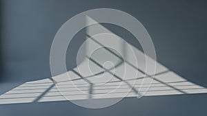 Geometric window light pattern casting abstract shadows on a smooth gray wall