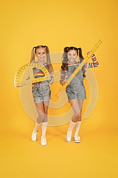 Geometry favorite subject. small girls hold ruler and protractor. little schoogirls yellow background. happy children