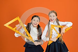 Without geometry life is pointless. Small girls are back to school. Cute schoolgirls holding triangles for lesson