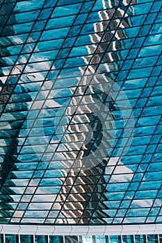 Geometry and lines of a modern business center. Clouds and buildings are reflected in the glass windows of the high-rise