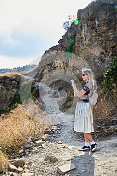 Georgia, Tbilisi - October 21, 2019: Attractive beautiful young girl who is female photographer traveller holding modern mirror