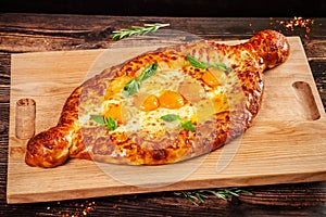 Georgian cuisine. Big khachapuri with 5 egg yolks, on a wooden board. A dish in a restaurant for a large company of people.