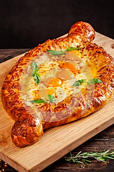 Georgian cuisine. Big khachapuri with 5 egg yolks, on a wooden board. A dish in a restaurant for a large company of people.