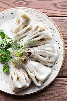 Georgian dumplings Khinkali with meat, greens on a wooden rustic table. Close up