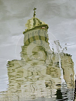 A Georgian Orthodox Church reflects in a shaky puddle in Georiga