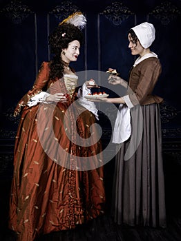 Georgian period woman wearing a silk gown and speaking to her maid