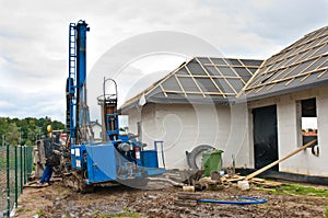 Geothermal drilling for house Heavy machine with drills next to newly constructed private house