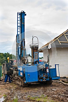 Geothermal drilling for house. Heavy machine with drills next to newly constructed private house