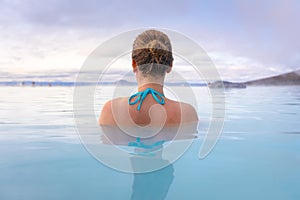 Geothermal spa in Iceland with young woman enjoying bathing in hot thermal pool with hotspring water for wellness and skin