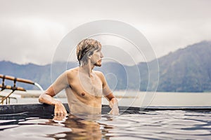 Geothermal spa. Man relaxing in hot spring pool. Young man enjoying bathing relaxed in a blue water lagoon, tourist