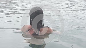 Geothermal spa. Woman relaxing in hot spring pool. Girl enjoying bathing opendoor basin with in warm mineral water 30fps