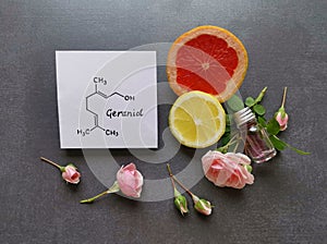 Geraniol, chemical formula with rose essential oil in a glass bottle, fresh citrus fruit, rose flowers and petals