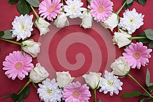 Gerberas, roses and chrysanthemums are laid out in the form of an oval on a table