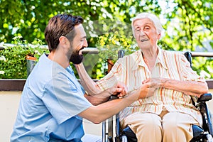 Geriatric nurse holding hand of old woman in rest home