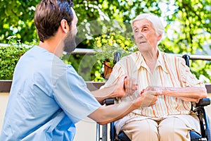 Geriatric nurse holding hand of old woman in rest home photo