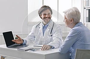Geriatrician explaining test results to senior patient on laptop photo