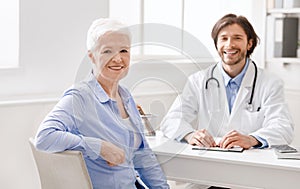 Geriatrician and senior female patient smiling at camera photo