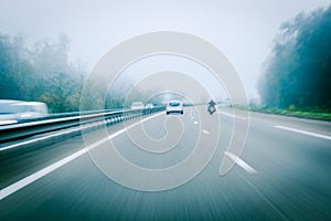 German autobahn highway blurred motion with white car and motorcyclist