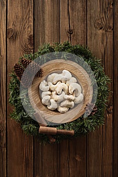 German Christmas pastry vanillekipferl. Crescent shaped biscuits in icing sugar in oak wood plate on fir tree wreath on rustic old