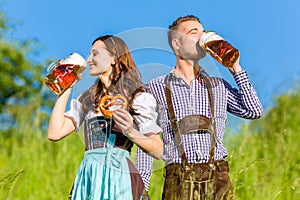 German couple in Tracht with beer, pretzel