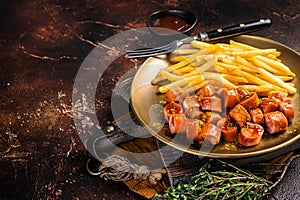 German currywurst sausage, curry wurst served with French fries. Dark background. Top view. Copy space