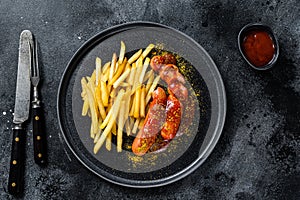 German currywurst Sausages with French fries on a plate. Black background. Top view