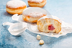 German donuts - berliner filled with strawberry jam with icing sugar