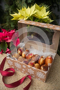 German donuts - berliner with filling and icing sugar in a box on a brown stone table. On Christmas decoration