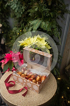 German donuts - berliner with filling and icing sugar in a box on a brown stone table. On Christmas decoration