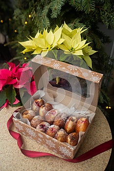German donuts - berliner with filling and icing sugar in a box on a brown stone table. On Christmas decoration