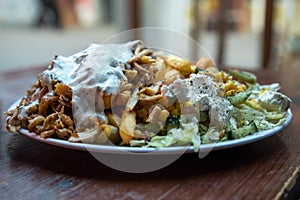 German DÃ¶ner Kebab dish with chicken, french fries, salad and garlic sauce on wooden table