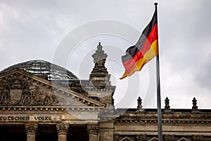 The German flag waves at the Bundestag, the building of the German parliament. Cloudy sky