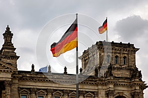 The German flag waves at the Bundestag, the building of the German parliament. Cloudy sky