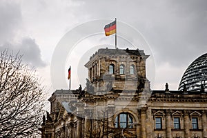 The German flag waves at the Bundestag, the building of the German parliament. Cloudy sky