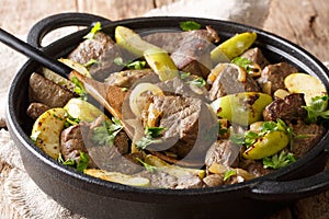 German food fried beef liver with green apples and onions close-up in a pan. horizontal