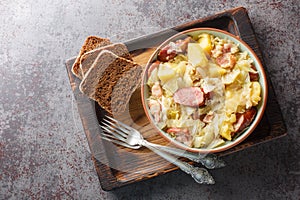 German Hunter Cabbage Stew with potatoes, sausage, bacon and onions close-up in a bowl on the table. Horizontal close-up in a bowl