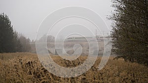 German ICE Train driving through foggy forest meadow