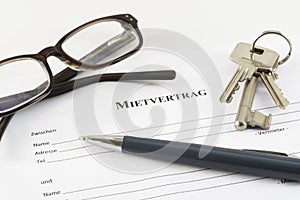 German lease agreement document with house keys, glasses and a