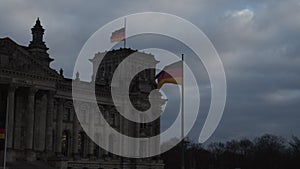 German national flags on poles at parliament building. Historic landmark at dusk. Deutscher Bundestag. Berlin, Germany