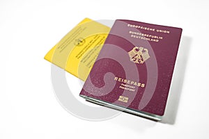 German Passport and yellow International Certificate of Vaccination book isolated on a white background, requirement to travel is