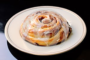 German pastry roll with raisins and sugar glazing called \'Rosinenschnecke\' on white plate